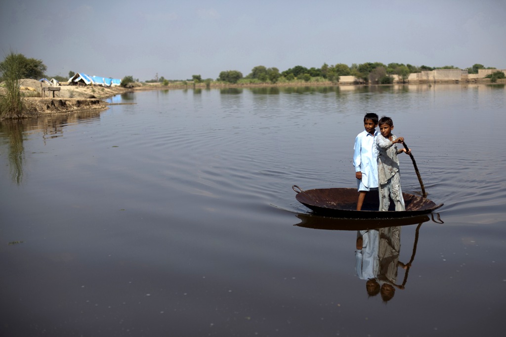 Boys use a large steel pot as a raft to cross an expanse of flood water in Pakistan. More than half a billion children across the world live in areas with extremely high flood risk. Photo: Unicef/2011/Zaidi